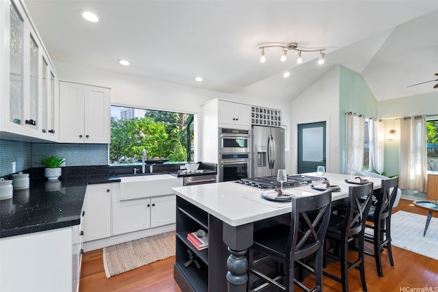 2633B Nahaku Pl Unit H, Honolulu, HI 96826 - kitchen featuring stainless steel appliances, open shelves, a center island, a breakfast bar area, and white cabinets