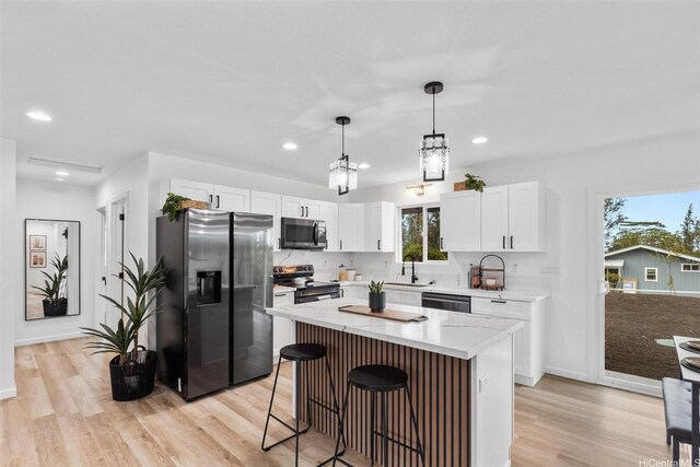 16-2073 Plumeria Dr, Pahoa, HI 96778 - kitchen featuring appliances with stainless steel finishes, light wood-style floors, white cabinetry, a breakfast bar area, and a kitchen island
