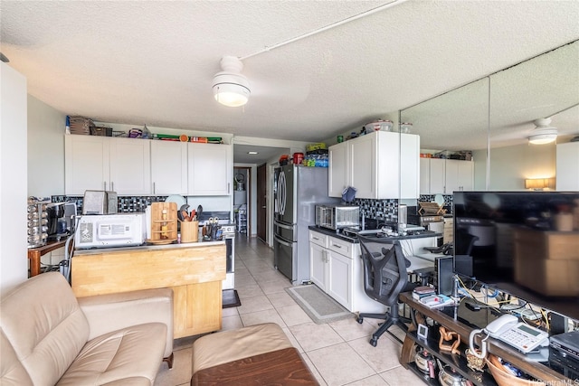 2211 Ala Wai Blvd Unit 3201, Honolulu, HI 96815 - kitchen featuring white microwave, light tile patterned floors, white cabinets, backsplash, and freestanding refrigerator