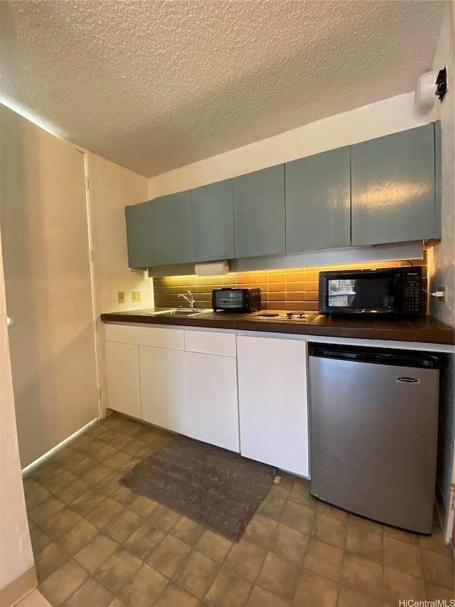 1750 Kalakaua Ave Unit 1507, Honolulu, HI 96826 - kitchen featuring black microwave, fridge, a textured ceiling, and decorative backsplash