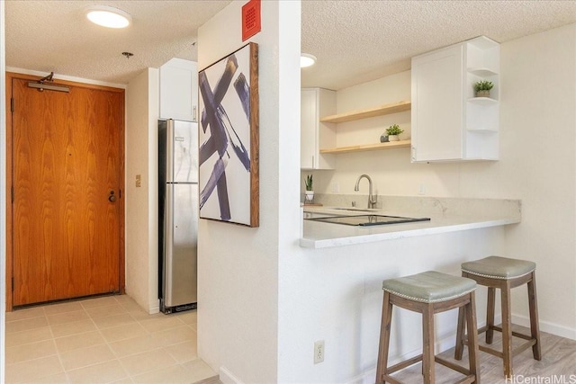 300 Wai Nani Way Unit 1715, Honolulu, HI 96815 - kitchen featuring open shelves, freestanding refrigerator, light countertops, a textured ceiling, and a breakfast bar area