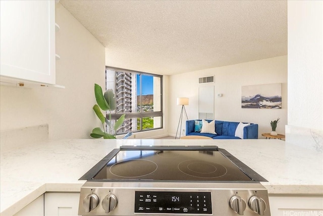 300 Wai Nani Way Unit 1715, Honolulu, HI 96815 - kitchen with black electric cooktop, white cabinetry, and a textured ceiling