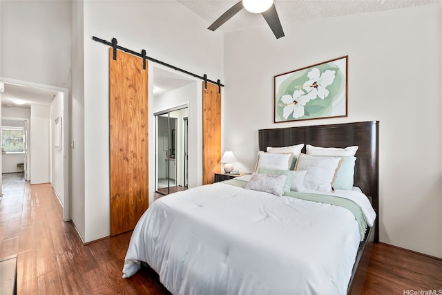 46-036 Aliikane Pl Unit 522, Kaneohe, HI 96744 - bedroom with a barn door, wood finished floors, a textured ceiling, ceiling fan, and a high ceiling