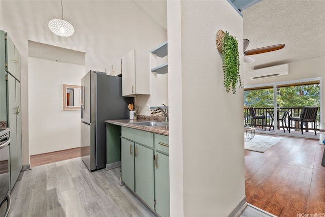 46-036 Aliikane Pl Unit 522, Kaneohe, HI 96744 - kitchen featuring a wall unit AC, green cabinets, light wood-style floors, a ceiling fan, and a towering ceiling