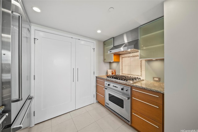 1177 Queen St Unit 4104, Honolulu, HI 96814 - kitchen featuring appliances with stainless steel finishes, wall chimney range hood, light tile patterned floors, light stone countertops, and brown cabinets