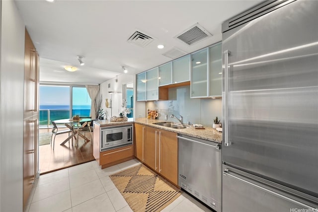 1177 Queen St Unit 4104, Honolulu, HI 96814 - kitchen featuring stainless steel appliances, light stone counters, light tile patterned floors, glass insert cabinets, and a peninsula