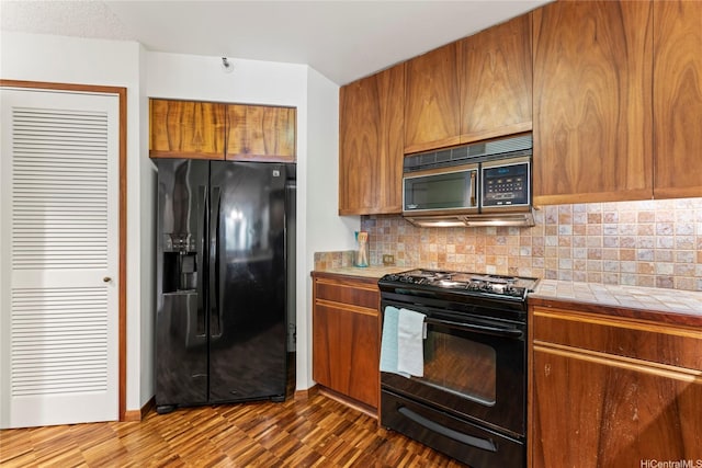 1525 Wilder Ave Unit 401, Honolulu, HI 96822 - kitchen with black appliances, tile counters, decorative backsplash, and brown cabinetry