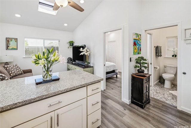92-6024 Kohi St, Kapolei, HI 96707 - kitchen with vaulted ceiling, ceiling fan, light stone counters, white cabinetry, and light wood finished floors