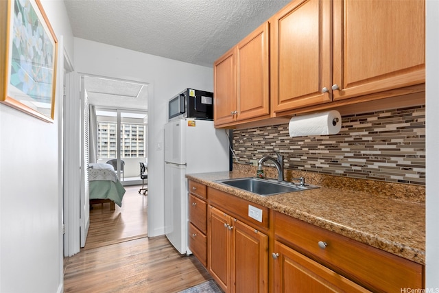 1720 Ala Moana Blvd Unit 1101B, Honolulu, HI 96815 - kitchen featuring decorative backsplash, light wood-style flooring, freestanding refrigerator, a textured ceiling, and brown cabinetry