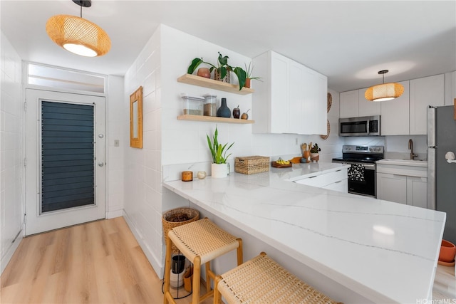920 Kaheka St Unit 25, Honolulu, HI 96814 - kitchen with appliances with stainless steel finishes, light wood-type flooring, open shelves, light stone counters, and a peninsula