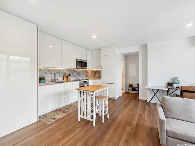 987 Queen St Unit 4112, Honolulu, HI 96814 - kitchen with stainless steel microwave, light wood-style flooring, tasteful backsplash, white cabinetry, and recessed lighting