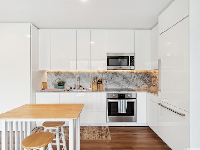 987 Queen St Unit 4112, Honolulu, HI 96814 - kitchen featuring stainless steel appliances, modern cabinets, dark wood-type flooring, white cabinets, and tasteful backsplash
