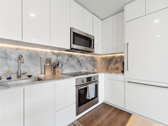 987 Queen St Unit 4112, Honolulu, HI 96814 - kitchen featuring stainless steel appliances, wood finished floors, white cabinetry, and backsplash