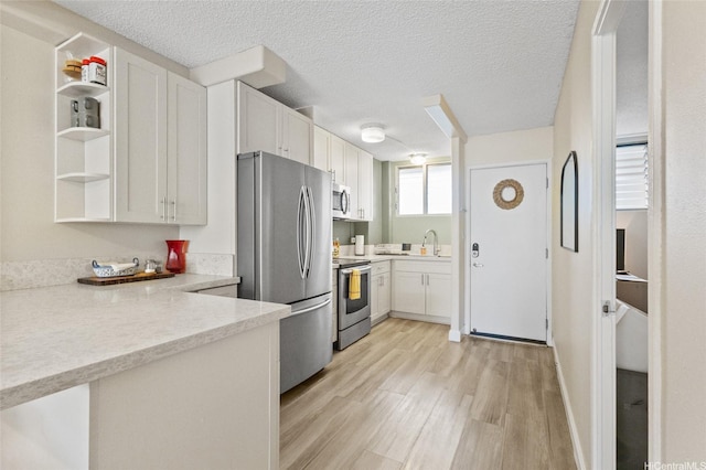 1684 Ala Moana Blvd Unit 251, Honolulu, HI 96815 - kitchen featuring appliances with stainless steel finishes, open shelves, light wood-style floors, white cabinets, and a textured ceiling