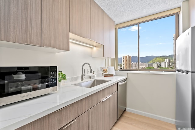 2444 Hihiwai St Unit 902, Honolulu, HI 96826 - kitchen featuring appliances with stainless steel finishes, a mountain view, modern cabinets, light wood-style floors, and a textured ceiling