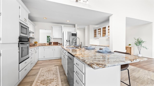 1373 Kaeleku St, Honolulu, HI 96825 - kitchen featuring stainless steel appliances, an island with sink, white cabinets, a breakfast bar area, and recessed lighting