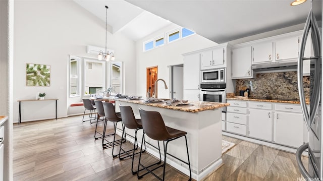 1373 Kaeleku St, Honolulu, HI 96825 - kitchen with stainless steel appliances, backsplash, white cabinets, under cabinet range hood, and high vaulted ceiling