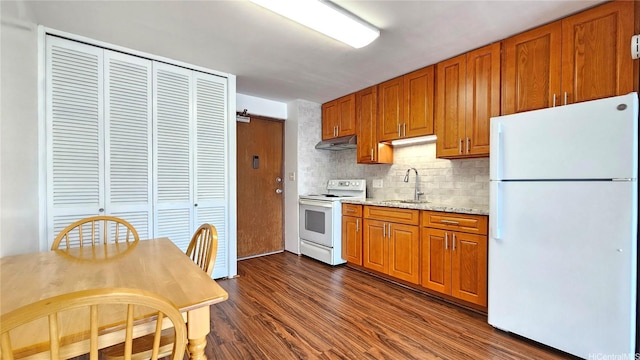 1655 Makaloa St Unit 903, Honolulu, HI 96814 - kitchen featuring white appliances, backsplash, dark wood-style flooring, brown cabinets, and under cabinet range hood