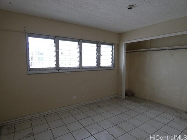 2421 Ala Wai Blvd Unit 1701, Honolulu, HI 96815 - unfurnished bedroom featuring a textured ceiling, a closet, and light tile patterned floors