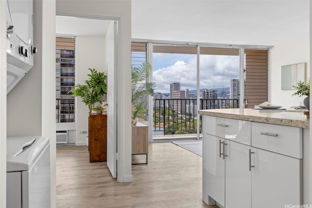 2345 Ala Wai Blvd Unit 1918, Honolulu, HI 96815 - kitchen featuring a wall of windows, washer / clothes dryer, light wood finished floors, healthy amount of natural light, and white cabinetry