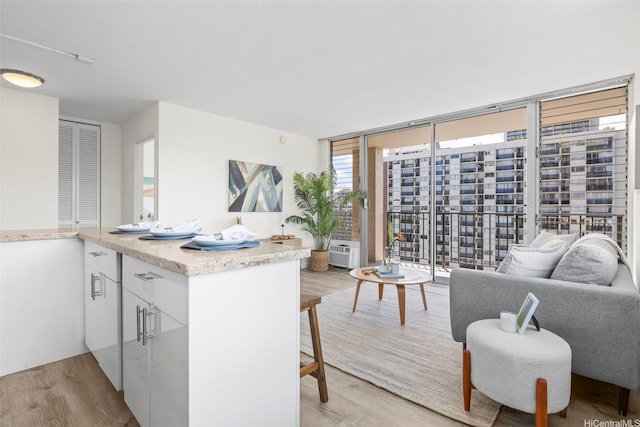 2345 Ala Wai Blvd Unit 1918, Honolulu, HI 96815 - kitchen featuring light wood finished floors, floor to ceiling windows, white cabinetry, a breakfast bar area, and open floor plan