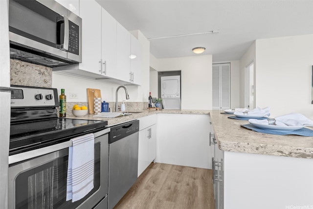 2345 Ala Wai Blvd Unit 1918, Honolulu, HI 96815 - kitchen with appliances with stainless steel finishes, stacked washer / drying machine, light wood finished floors, a peninsula, and white cabinets