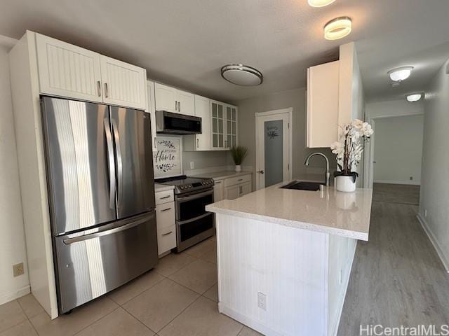 94-586 Lumiauau St Unit N104, Waipahu, HI 96797 - kitchen featuring stainless steel appliances, light countertops, white cabinets, glass insert cabinets, and a peninsula