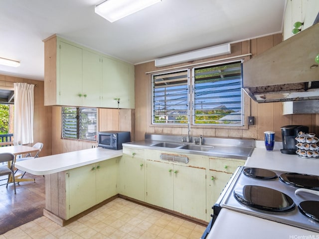 1114 8th Ave, Honolulu, HI 96816 - kitchen featuring black microwave, a peninsula, light countertops, exhaust hood, and wooden walls