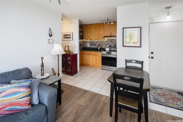 2115 Ala Wai Blvd Unit 1003, Honolulu, HI 96815 - kitchen with stainless steel electric range oven, track lighting, light wood-style floors, tasteful backsplash, and a textured ceiling