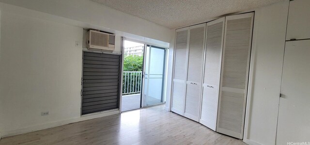1516 Ward Ave Unit 207, Honolulu, HI 96822 - unfurnished bedroom with access to exterior, a textured ceiling, light wood-style floors, a wall mounted air conditioner, and a closet