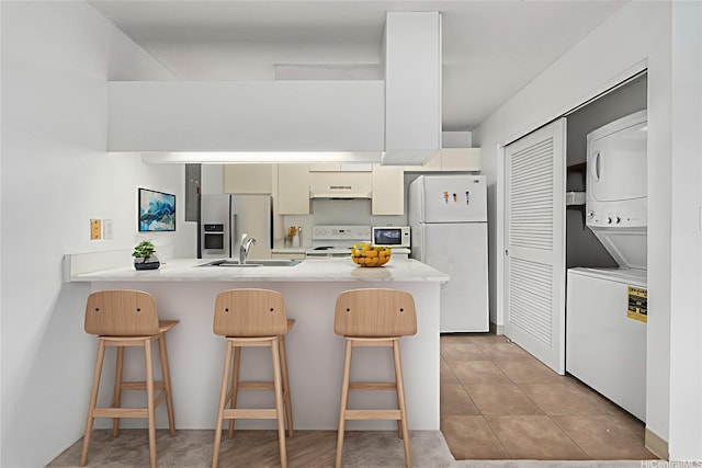 94-1079 Kepakepa St Unit H8, Waipahu, HI 96797 - kitchen featuring white appliances, stacked washer and clothes dryer, ventilation hood, a peninsula, and a breakfast bar