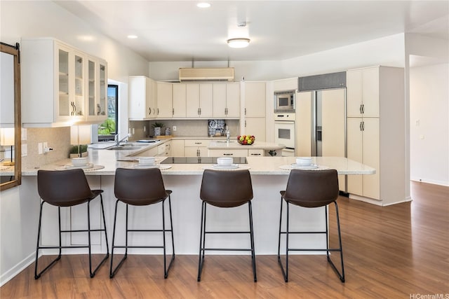 5926 Kalanianaole Hwy, Honolulu, HI 96821 - kitchen featuring built in appliances, a peninsula, tasteful backsplash, glass insert cabinets, and dark wood-type flooring