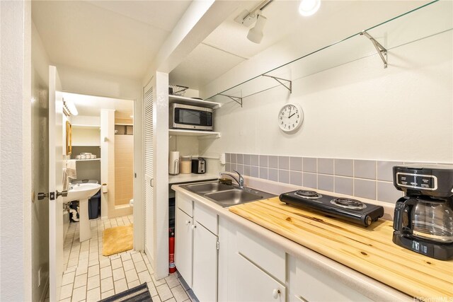 5926 Kalanianaole Hwy, Honolulu, HI 96821 - kitchen with stainless steel microwave, white cabinetry, light countertops, decorative backsplash, and light tile patterned floors