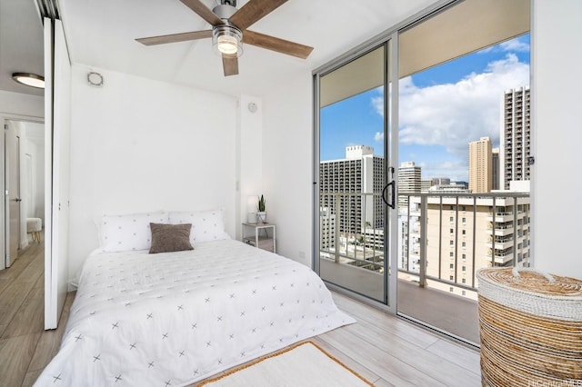 2575 Kuhio Ave Unit 1702, Honolulu, HI 96815 - bedroom featuring a wall of windows, wood finished floors, a view of city, access to outside, and a ceiling fan