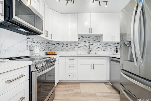 2575 Kuhio Ave Unit 1702, Honolulu, HI 96815 - kitchen with appliances with stainless steel finishes, white cabinets, tasteful backsplash, track lighting, and light wood-style floors