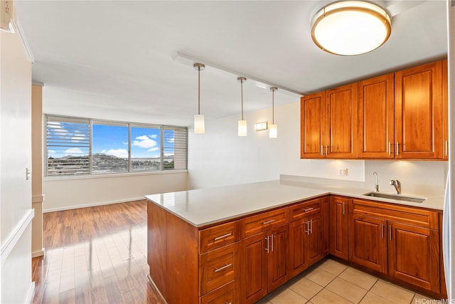46-255 Kahuhipa St Unit A1100, Kaneohe, HI 96744 - kitchen with brown cabinetry, light countertops, a peninsula, decorative light fixtures, and light wood-type flooring