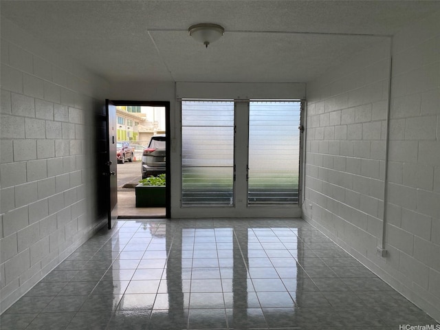 1118 Pua Ln Unit 113, Honolulu, HI 96817 - empty room featuring concrete block wall, healthy amount of natural light, and dark tile patterned floors