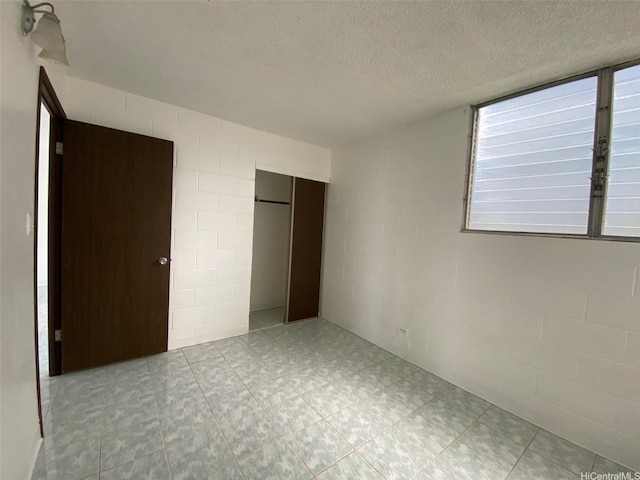 1118 Pua Ln Unit 113, Honolulu, HI 96817 - unfurnished bedroom with concrete block wall, a closet, and a textured ceiling