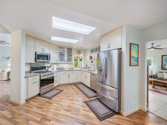 1586 Paukiki St, Kailua, HI 96734 - kitchen with appliances with stainless steel finishes, a skylight, light wood finished floors, glass insert cabinets, and light stone counters