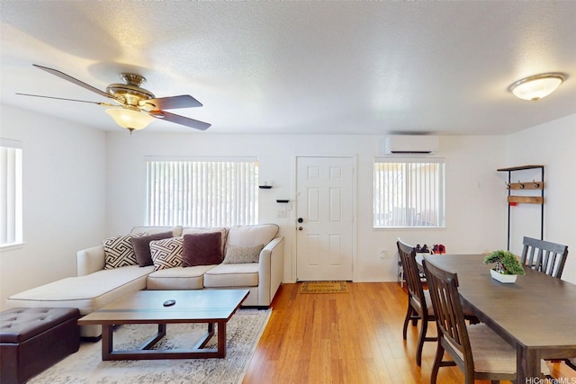 91-1105 Namahoe St Unit 2G, Kapolei, HI 96707 - living room with a wall mounted AC, plenty of natural light, light wood-type flooring, a ceiling fan, and a textured ceiling
