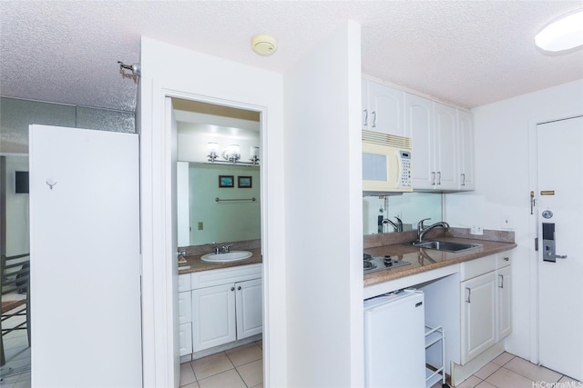 1700 Ala Moana Blvd Unit 603, Honolulu, HI 96815 - kitchen featuring white microwave, light tile patterned floors, white cabinetry, and a textured ceiling