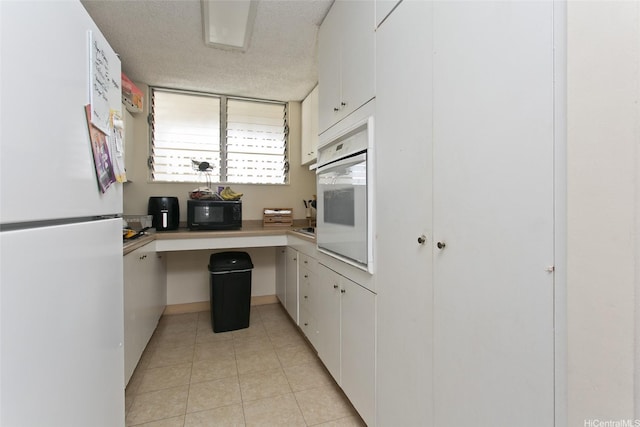 469 Ena Rd Unit 2304, Honolulu, HI 96815 - kitchen with white appliances, light tile patterned floors, white cabinets, light countertops, and a textured ceiling
