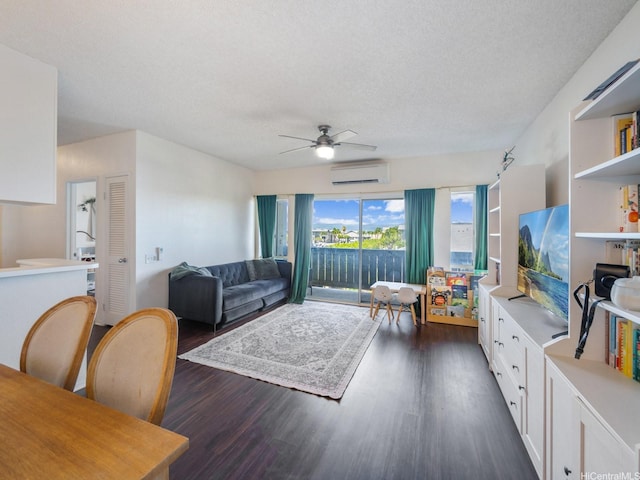 91-265 Hanapouli Cir Unit 16J, Ewa Beach, HI 96706 - living room featuring an AC wall unit, dark wood-type flooring, a ceiling fan, and a textured ceiling