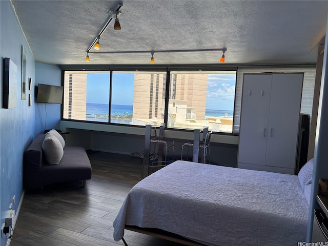 1700 Ala Moana Blvd Unit 2001, Honolulu, HI 96815 - bedroom with rail lighting, wood finished floors, and a textured ceiling
