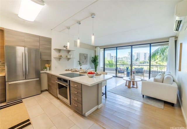 2333 Kapiolani Blvd Unit 311, Honolulu, HI 96826 - kitchen featuring appliances with stainless steel finishes, a peninsula, open floor plan, light countertops, and a wall unit AC