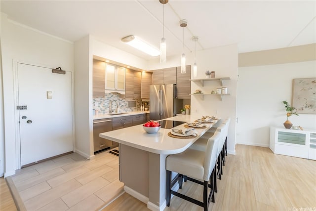 2333 Kapiolani Blvd Unit 311, Honolulu, HI 96826 - kitchen featuring stainless steel appliances, light countertops, a kitchen breakfast bar, decorative backsplash, and a peninsula