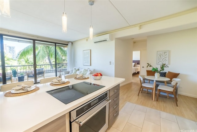 2333 Kapiolani Blvd Unit 311, Honolulu, HI 96826 - kitchen featuring black electric cooktop, stainless steel oven, a wall mounted air conditioner, light countertops, and pendant lighting