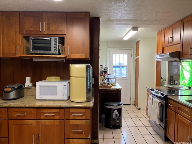 1617 Kamehameha Iv Rd, Honolulu, HI 96819 - kitchen featuring white microwave, electric range, under cabinet range hood, light tile patterned flooring, and brown cabinets