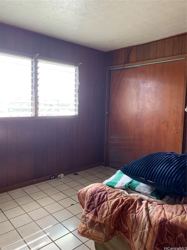 1617 Kamehameha Iv Rd, Honolulu, HI 96819 - bedroom featuring a textured ceiling, light tile patterned floors, a closet, and wooden walls