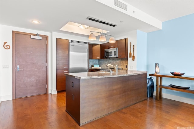 1837 Kalakaua Ave Unit 2209, Honolulu, HI 96815 - kitchen with stainless steel appliances, wood finished floors, a peninsula, light stone countertops, and tasteful backsplash